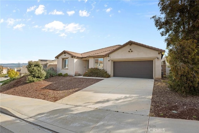 view of front facade featuring concrete driveway, a tile roof, a garage, and stucco siding