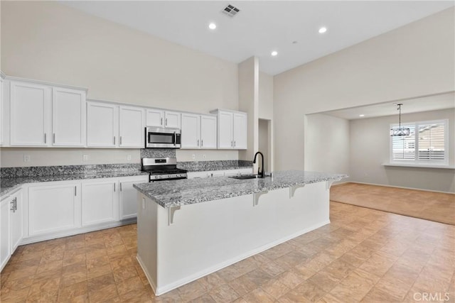 kitchen featuring light stone countertops, visible vents, a high ceiling, a sink, and stainless steel appliances