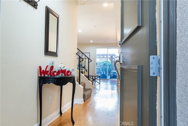 hall featuring recessed lighting, light wood-type flooring, stairway, and baseboards