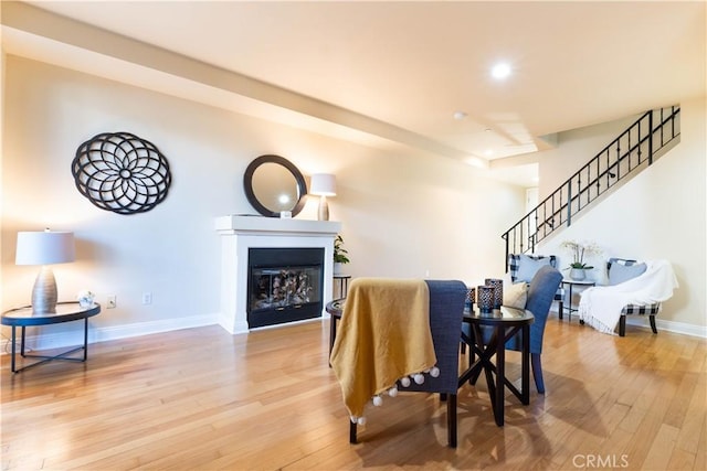 dining room featuring a glass covered fireplace, baseboards, recessed lighting, stairway, and hardwood / wood-style flooring