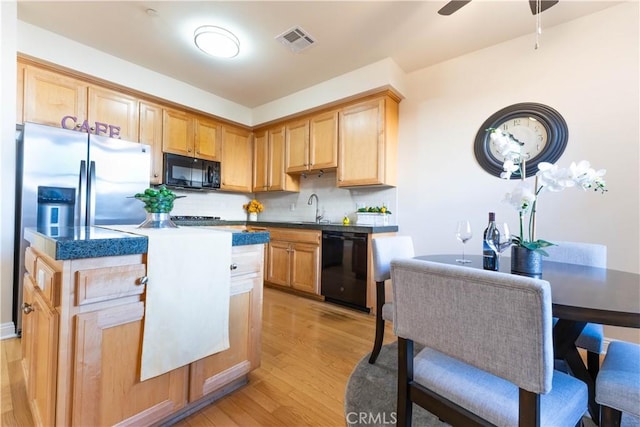 kitchen featuring tasteful backsplash, light wood-type flooring, visible vents, black appliances, and a sink
