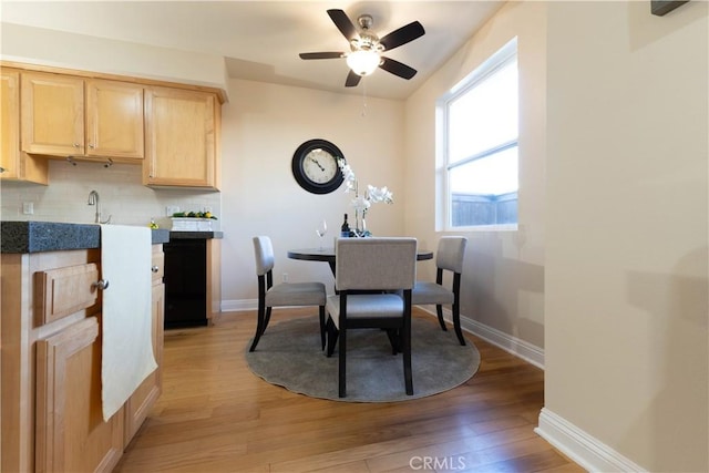 dining room with light wood-style flooring, a ceiling fan, and baseboards