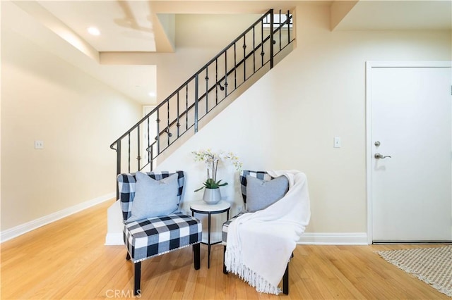 sitting room with baseboards, recessed lighting, wood finished floors, and stairs