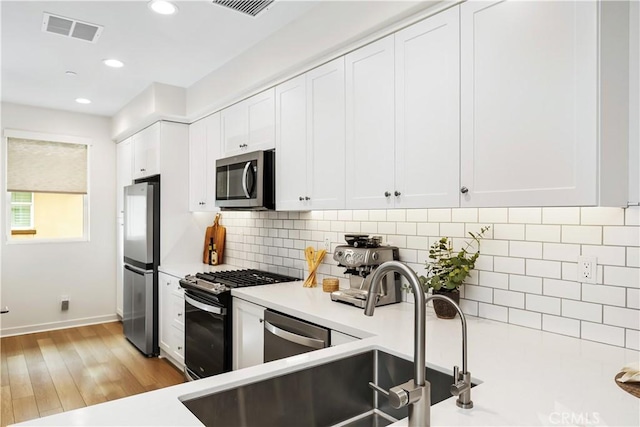 59 Sanctuary Ln, Mission Viejo, CA 92692 - kitchen with light countertops, white cabinets, visible vents, decorative backsplash, and appliances with stainless steel finishes