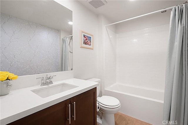 full bath with visible vents, shower / tub combo with curtain, toilet, wood finished floors, and vanity