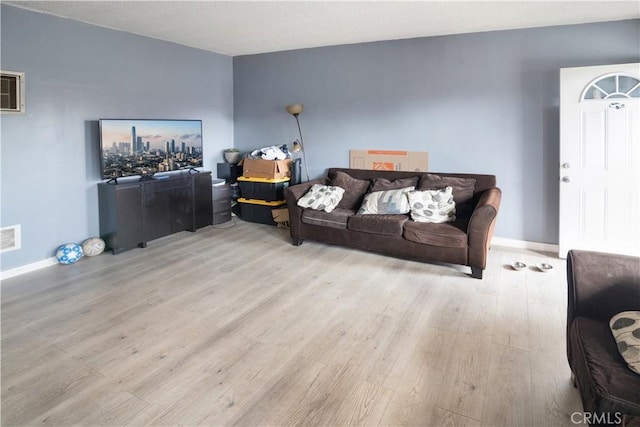 living room with visible vents, baseboards, and wood finished floors
