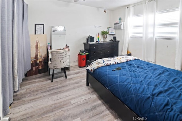 bedroom with light wood-style flooring and a wall mounted air conditioner
