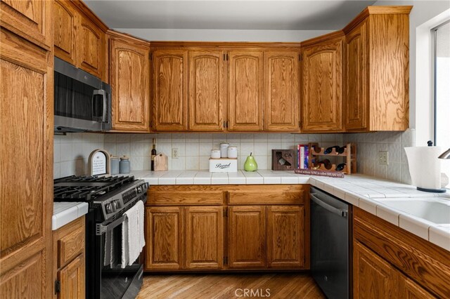1492 Coolidge Ave, Pasadena, CA 91104 - kitchen featuring stainless steel appliances, brown cabinets, backsplash, and wood finished floors