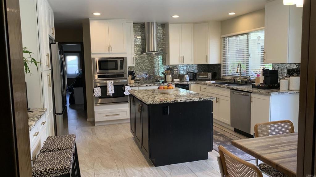 kitchen featuring stainless steel appliances, a center island, decorative backsplash, and wall chimney range hood