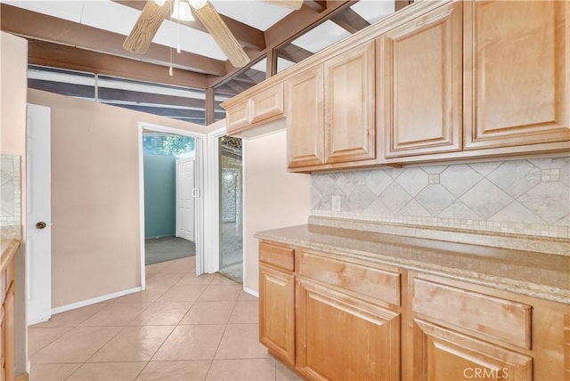 kitchen featuring light tile patterned floors, baseboards, ceiling fan, and backsplash