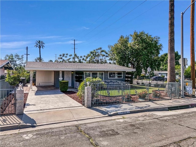 ranch-style house with driveway, a fenced front yard, and an attached carport