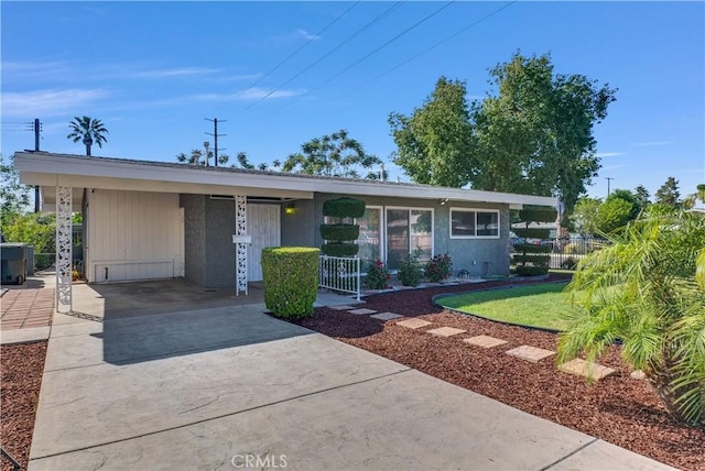 view of front of house with concrete driveway, fence, and an attached carport