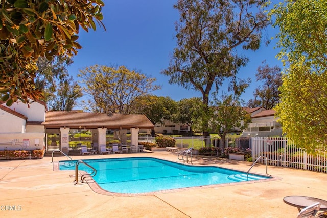 community pool with a patio and fence