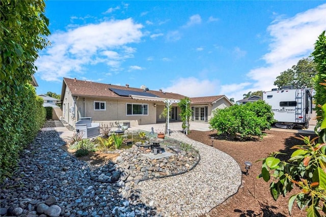 back of house with a patio, stucco siding, and solar panels