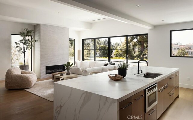3 Rue Valbonne, Newport Beach, CA 92660 - kitchen featuring light wood-style floors, an island with sink, modern cabinets, stainless steel microwave, and a sink