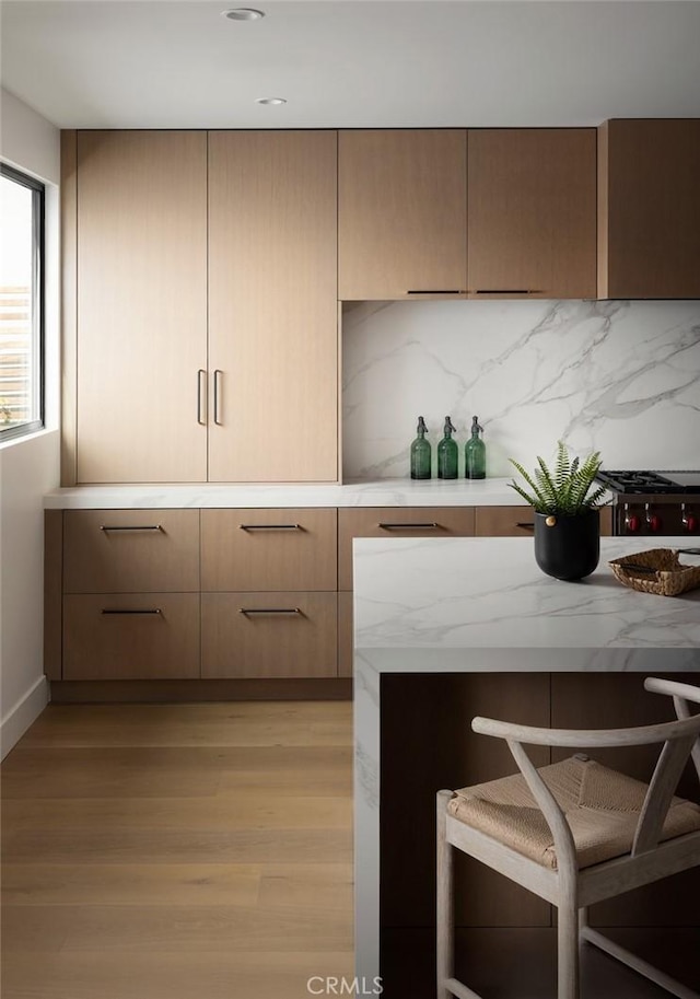 3 Rue Valbonne, Newport Beach, CA 92660 - kitchen with tasteful backsplash, modern cabinets, a kitchen bar, light wood-style floors, and light stone counters