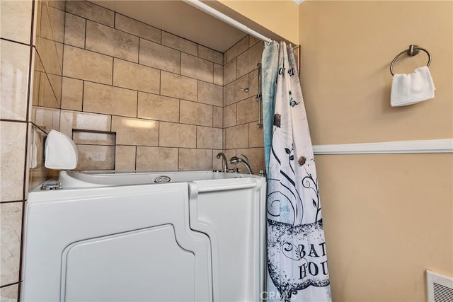 full bath featuring a washtub, a shower with shower curtain, washer / dryer, and visible vents