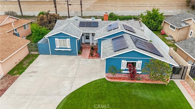 view of front of house featuring roof mounted solar panels, a shingled roof, a front lawn, a fenced backyard, and a gate