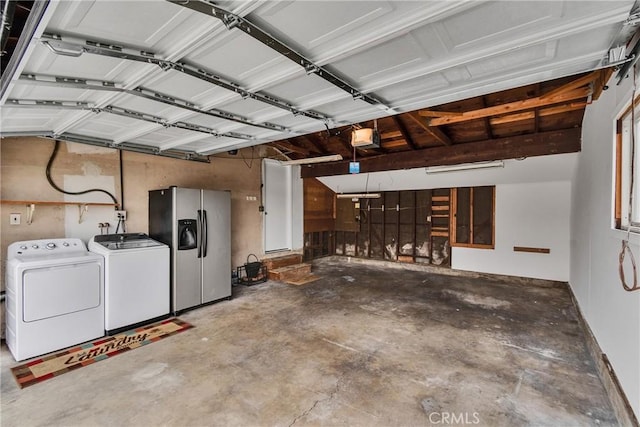 garage with stainless steel fridge with ice dispenser, independent washer and dryer, and a garage door opener