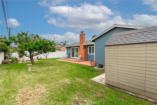 back of house featuring a yard, roof with shingles, a chimney, and a fenced backyard