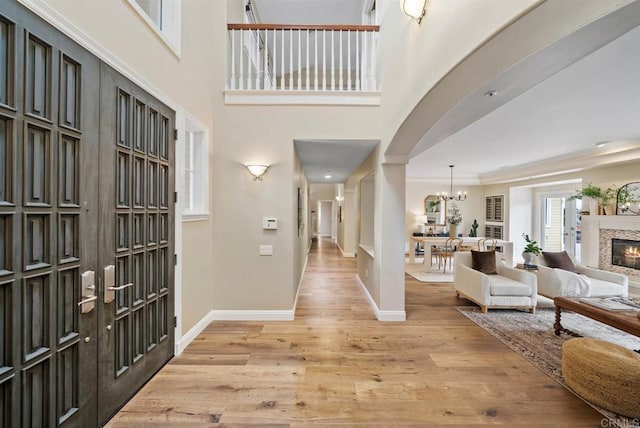 753 Jacquelene Ct, Encinitas, CA 92024 - entrance foyer featuring light wood-style flooring, a chandelier, baseboards, a glass covered fireplace, and crown molding