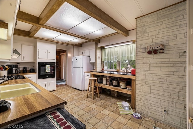 kitchen with white cabinetry, black appliances, beamed ceiling, coffered ceiling, and a sink