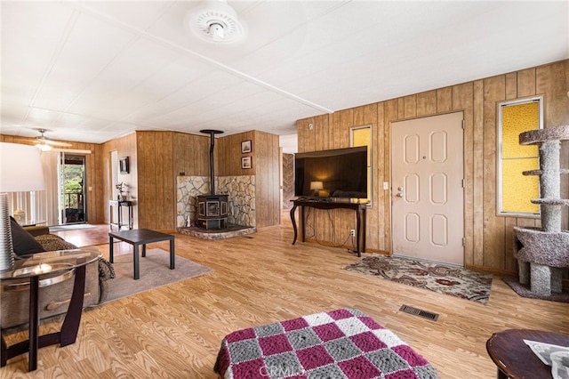 7395 Cardinal Rd, Corning, CA 96021 - living room featuring wooden walls, a wood stove, wood finished floors, and a ceiling fan