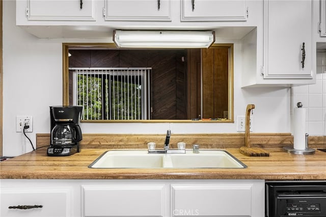 kitchen featuring light countertops, dishwasher, a sink, and white cabinetry