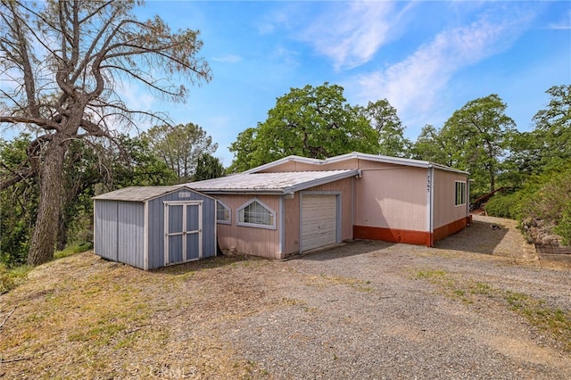 exterior space with a storage unit, a garage, driveway, and an outdoor structure