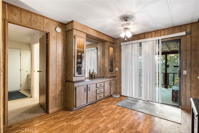 interior space with light wood-style flooring, wood walls, and a ceiling fan