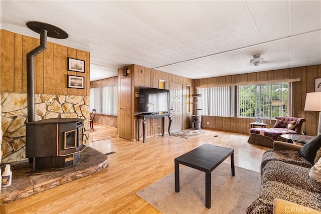 living area with wood finished floors, wooden walls, and a wood stove