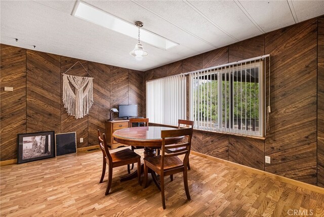 7395 Cardinal Rd, Corning, CA 96021 - dining space with wood walls, light wood finished floors, a textured ceiling, and a skylight