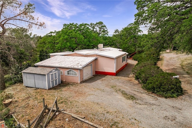 back of property featuring a storage shed, an outdoor structure, and dirt driveway