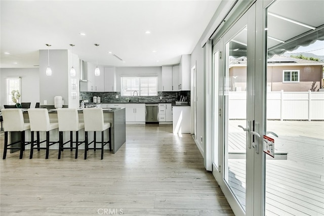 1430 Irving Ave, Glendale, CA 91201 - kitchen featuring light wood-style floors, white cabinetry, dishwasher, a breakfast bar area, and backsplash