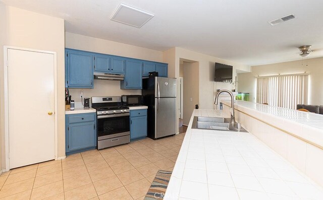 43564 Amazon St, Hemet, CA 92544 - kitchen featuring appliances with stainless steel finishes, blue cabinetry, tile countertops, a sink, and under cabinet range hood