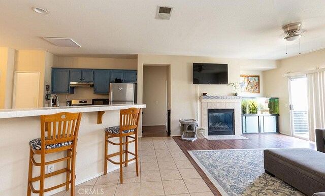43564 Amazon St, Hemet, CA 92544 - kitchen featuring refrigerator, under cabinet range hood, a breakfast bar, tile countertops, and open floor plan