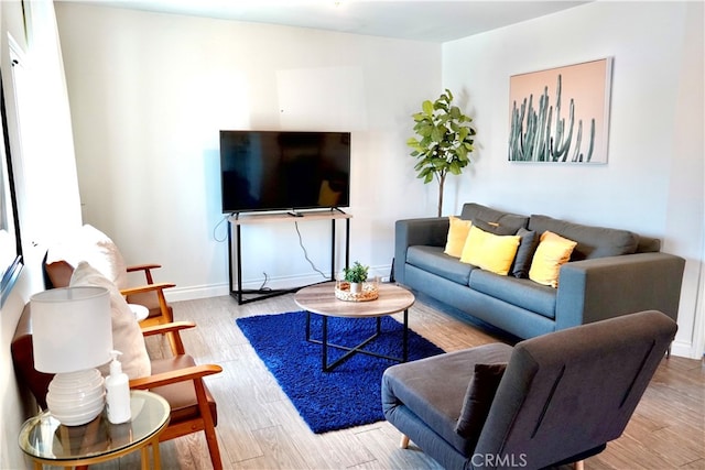 living area with baseboards and wood finished floors