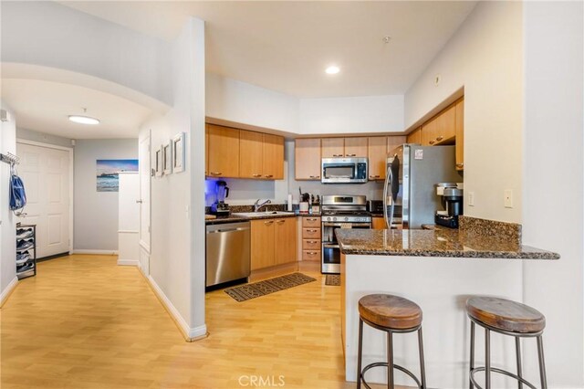 1180 Civic Center Dr Unit B21, Oceanside, CA 92054 - kitchen with appliances with stainless steel finishes, a peninsula, light wood-style floors, a breakfast bar, and a sink
