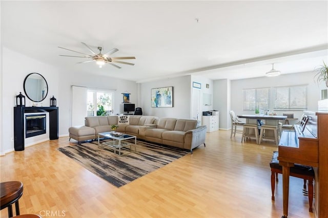 1180 Civic Center Dr Unit B21, Oceanside, CA 92054 - living area featuring light wood-style floors, a ceiling fan, a glass covered fireplace, and baseboards