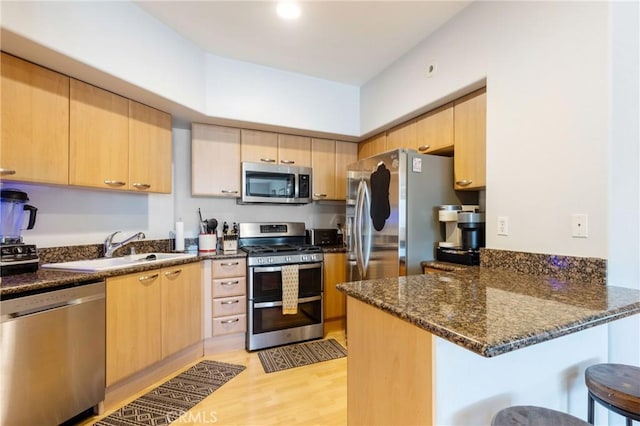 1180 Civic Center Dr Unit B21, Oceanside, CA 92054 - kitchen featuring appliances with stainless steel finishes, light brown cabinets, a sink, a peninsula, and dark stone countertops