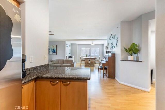 1180 Civic Center Dr Unit B21, Oceanside, CA 92054 - kitchen featuring a peninsula, light wood-type flooring, freestanding refrigerator, open floor plan, and dark stone counters