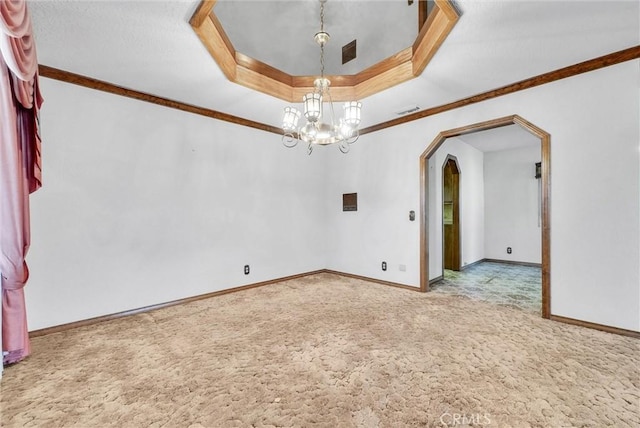 empty room with a raised ceiling, arched walkways, carpet floors, baseboards, and a notable chandelier