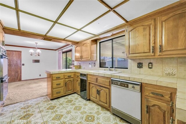kitchen with a peninsula, a sink, an inviting chandelier, white dishwasher, and brown cabinets