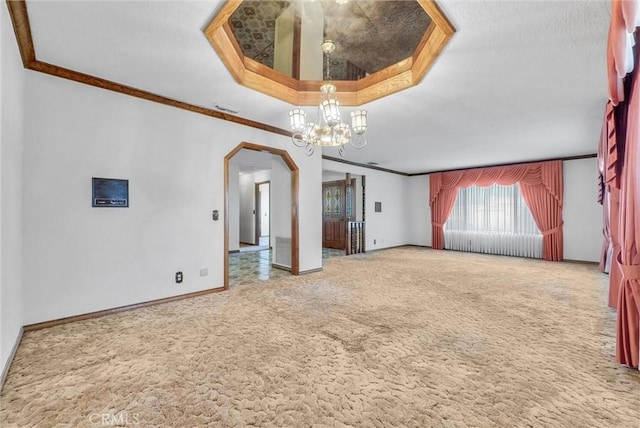 empty room featuring carpet, a raised ceiling, visible vents, arched walkways, and a chandelier
