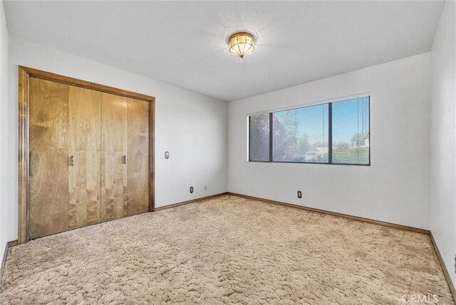 unfurnished bedroom featuring a closet, carpet flooring, and baseboards