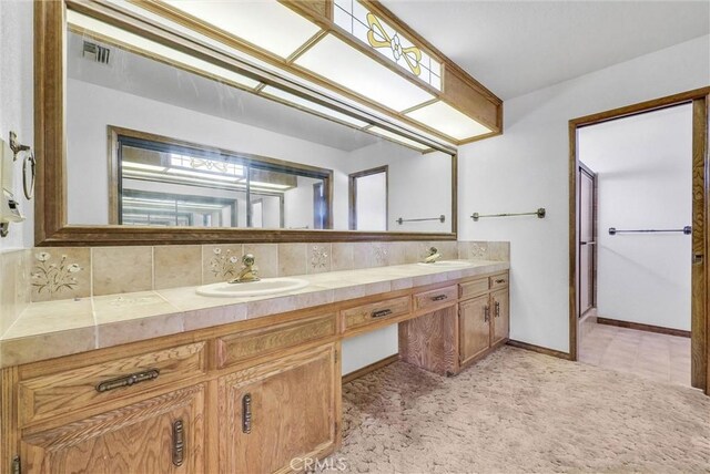 bathroom featuring tasteful backsplash, a sink, visible vents, and double vanity
