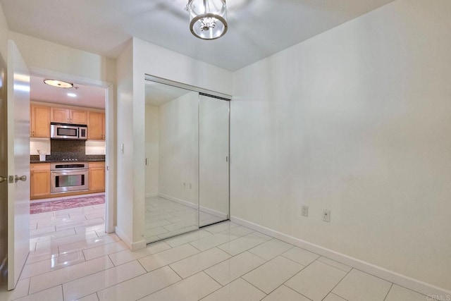 1150 J St Unit 117, San Diego, CA 92101 - unfurnished bedroom featuring baseboards, a closet, light tile patterned flooring, and a chandelier