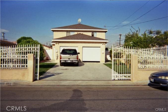 traditional home featuring fence, a gate, a garage, and concrete driveway