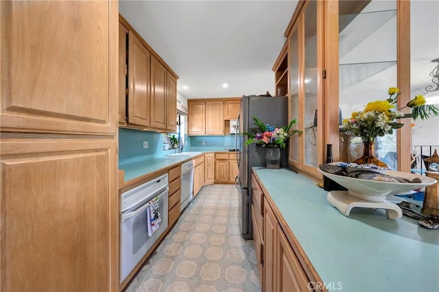 kitchen featuring recessed lighting, white appliances, glass insert cabinets, light countertops, and light floors