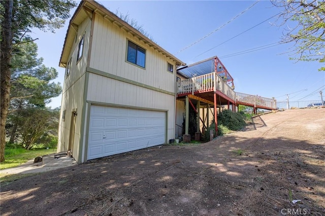 view of home's exterior featuring a garage, aphalt driveway, and a wooden deck